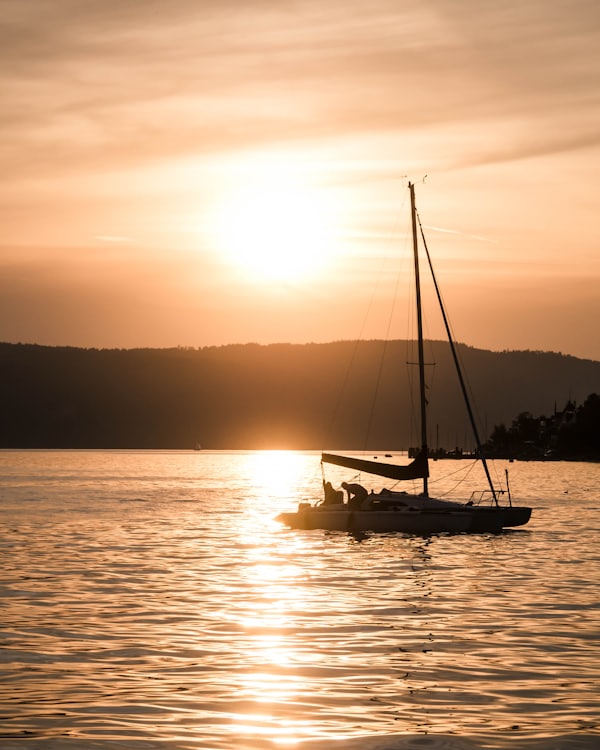 A sailboat resting on golden water at sunset