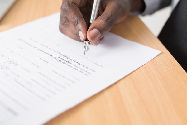 A hand signing a commitment with care