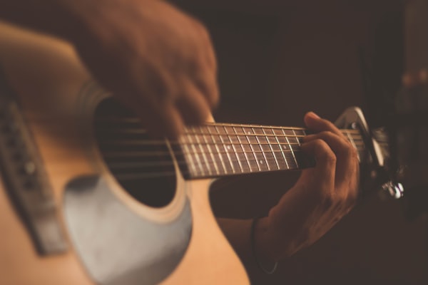 Hands playing an acoustic guitar in warm light